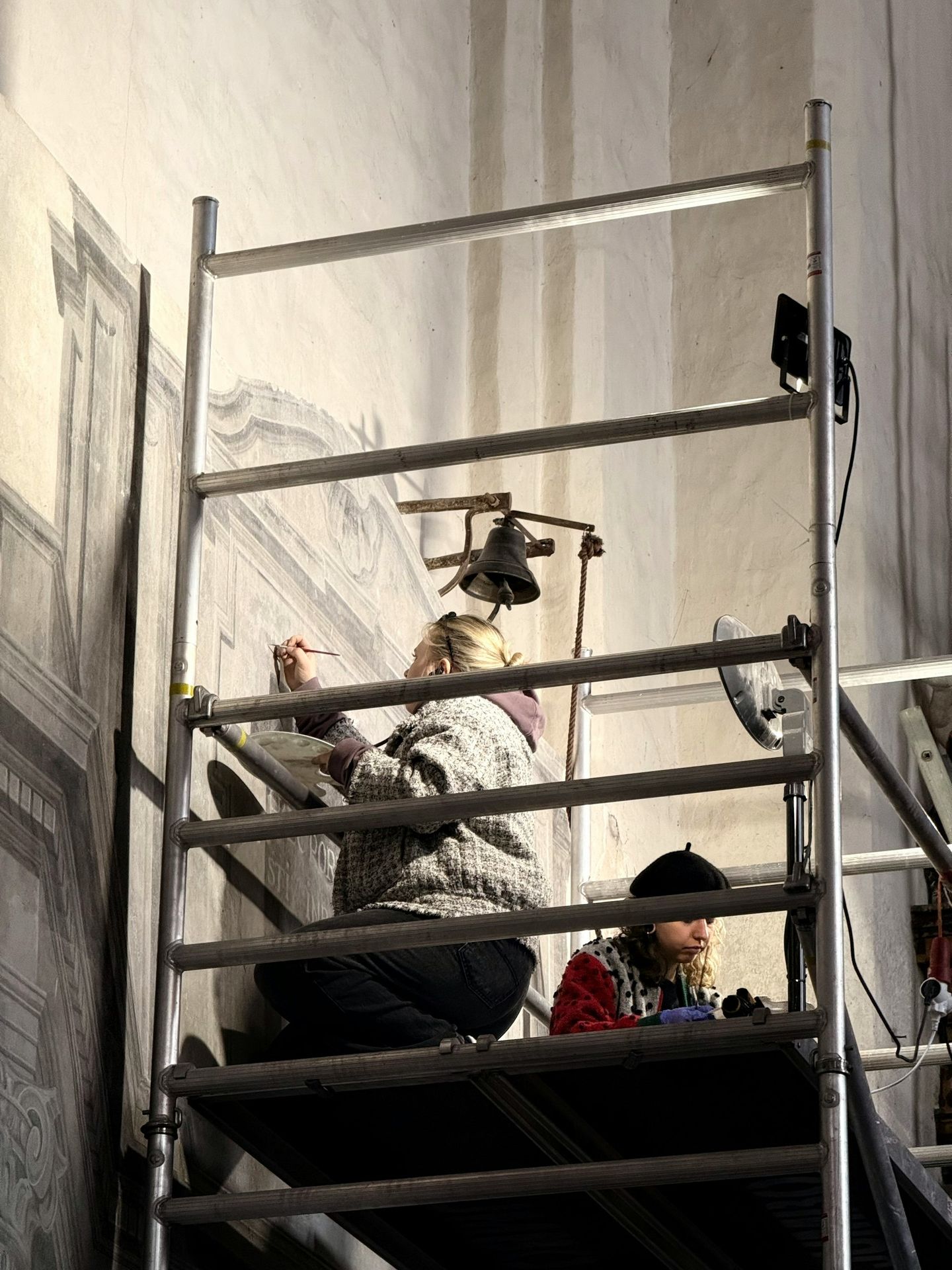 Artists restoring a large mural on scaffolding
